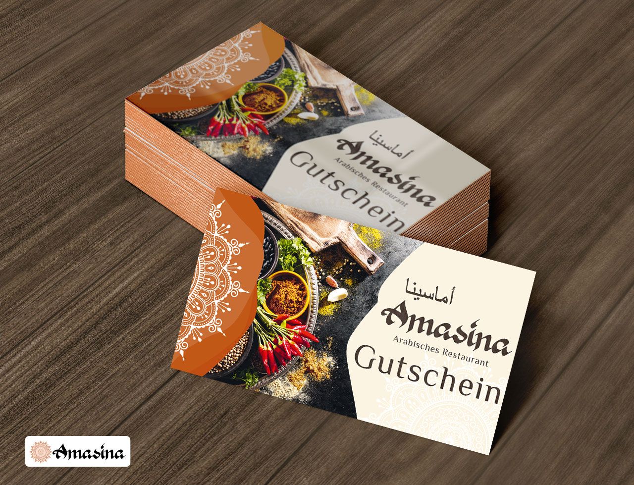 Gutscheinkarten für das arabische Restaurant Amasina mit Gewürzmotiven, gestapelt auf einem Holztisch.